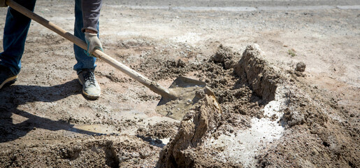 Worker prepare concrete with shovel at construction site.
