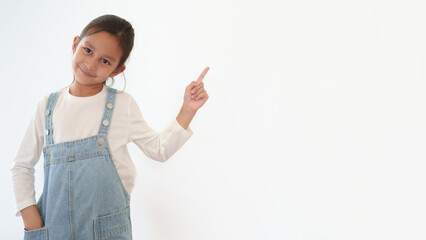 Isolated of happy and healthy 6 years old asian little girl is standing and pointing up on the white background. Concept of thinking, idea, expression, advertising, people, lifestyle.