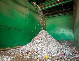A pile of scrap metal and trash with some more pouring onto the pile at a dump