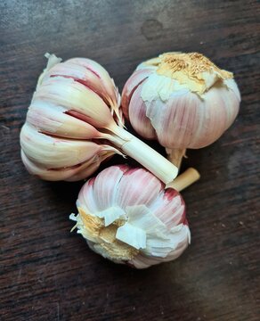 evocative close-up image of three bunches of garlic on dark wooden background
