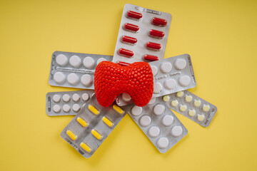 Red thyroid gland and pills on a yellow