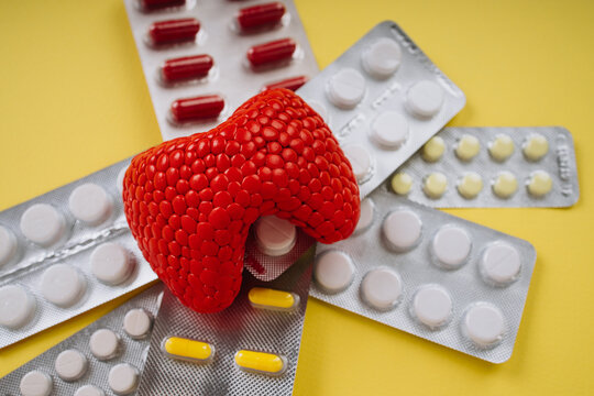 Red thyroid gland and pills on a yellow background close-up