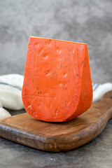 Red gouda cheese. Guoda cheese with sun-dried tomatoes and basil on a dark background. Dutch...
