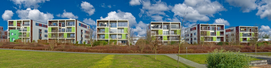 Panorama mit quaderförmigen, modernen Wohhäusern in einem Neubaugebiet in Frankfurrt am Main, bei sonnigem Wetter und aufgelockerter Beweölkung