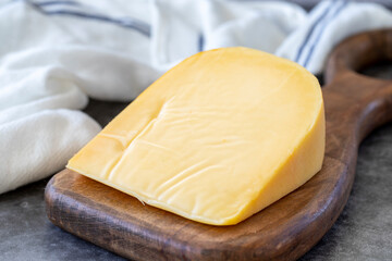 Yellow gouda cheese. Hard Dutch gouda cheese, on dark background. close up - obrazy, fototapety, plakaty