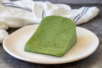 Green gouda cheese. Gouda cheese with basil on a dark background. Dutch cheese. close up