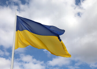 Blue and yellow flag of Ukraine with blue sky and clouds