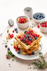 Traditional belgian waffles with fresh berries, raspberries, currant, blueberries, maple syrup, thyme on pink background. Summer concept. Selective focus.