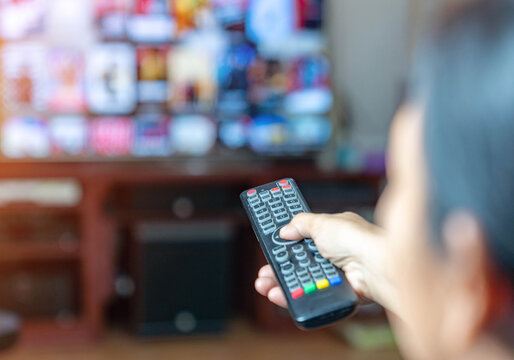 Women press button on remote control for change chanel on smart tv program.