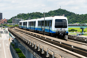 Wenhu or Brown line of Taipei MRT in Taiwan. View of a train running on the elevated track of the Taipei subway system under a clear blue sky.