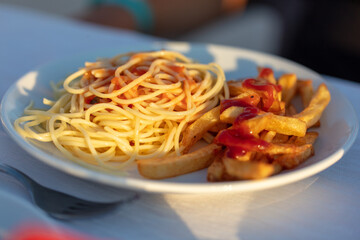 fried french fries with pasta on a white plate on the table.