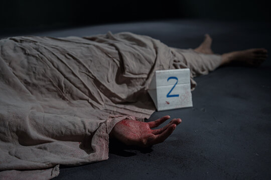 Victim of violent crime scene with cover sheet and evidence marker. Criminal and murder concept
