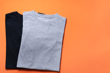 close up of rolled t shirt clothes on orange table background, travel lifestyle concept - obrazy, fototapety, plakaty