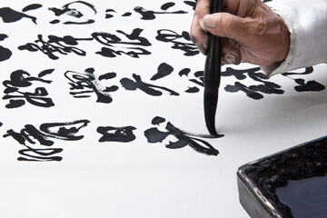a man is practicing callingraphy using a brush pen on white paper