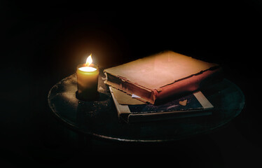 Vintage still life with lighting frame candle and old book in dark background