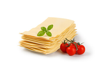 Lasagna sheets in stack with tomatoes and basil. Uncooked lasagna pasta isolated on white background. Clipping path.