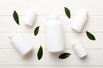 supplement pills with medicine bottle health care and medical top view. Vitamin tablets. Top view mockup bottle for pills and vitamins with green leaves, natural organic bio supplement, copy space