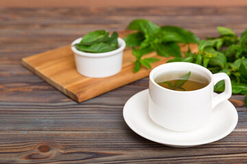 Cup of mint tea on table background. Green tea with fresh mint top view with copy space