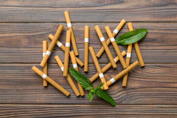Menthol cigarettes and fresh mint leaves on colored background, Many cigarettes stacked together...