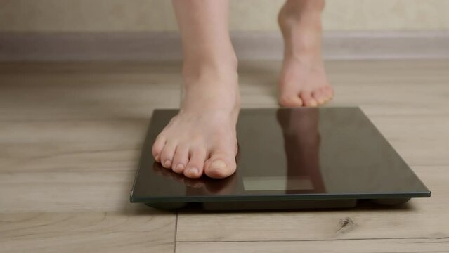Feet of a woman standing on the scales for weighing.