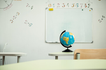 The Globe stands on the desk in the school classroom against the white school board. Planet Earth....