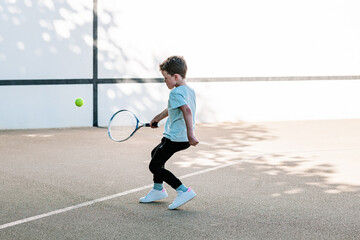 Boy learning to play tennis on street