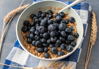 Breakfast cereal porridge with oats, amaranth, quinoa and fresh blueberries in a bowl with spoon