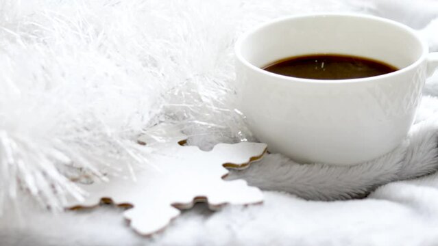 cup of hot black espresso coffee on christmas background white garland and wooden manual diy painted snowflake shape.gray blanket.coffee steam slow motion hd video.cozy home