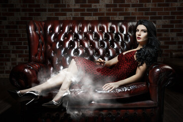 girl smokes a cigar on the bed. smoke in a dark room