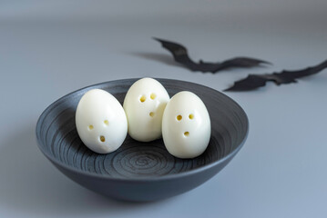 Ghost eggs for Halloween kid's breakfast in dark bowl over gray background.