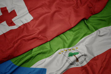 waving colorful flag of equatorial guinea and national flag of Tonga .