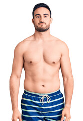 Fototapeta premium Young handsome man wearing swimwear looking sleepy and tired, exhausted for fatigue and hangover, lazy eyes in the morning.