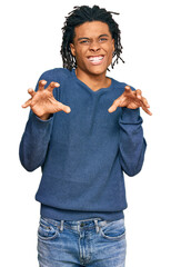 Young african american man wearing casual winter sweater smiling funny doing claw gesture as cat,...