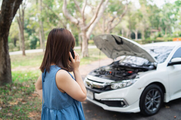 Fototapeta na wymiar Asian woman calling garage after car breaks down. woman opening car hood and call to insurance or someone to help after the car breaks down, park on the side of the road. Transportation concept.