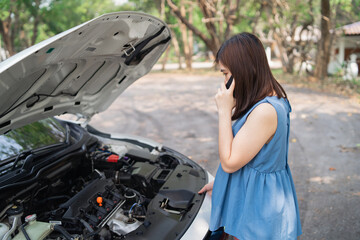 Asian woman calling garage after car breaks down. woman opening car hood and call to insurance or...