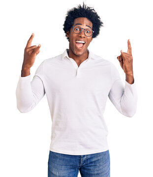 Handsome african american man with afro hair wearing casual clothes and glasses shouting with crazy expression doing rock symbol with hands up. music star. heavy music concept.