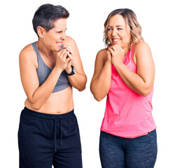 Couple of women wearing sportswear laughing nervous and excited with hands on chin looking to the side
