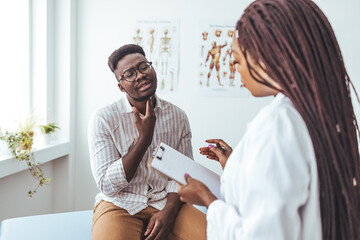 Discussing a sore throat at a doctor's appointment. Shot of a doctor examining a man’s throat during a consultation. Patient showing pain at Throat to her otolaryngologist.