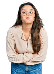 Obraz premium Young hispanic girl wearing casual clothes and glasses puffing cheeks with funny face. mouth inflated with air, catching air.