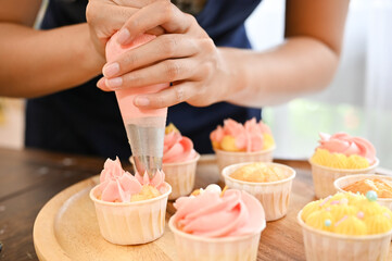 Woman using cream squeeze bag to decorating the cupcake, making cupcake