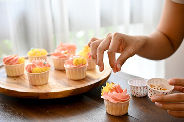 A female baker garnishing her homemade cupcake with almond slices.