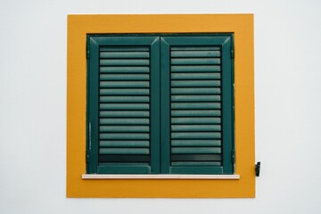 Window with a yellow frame and green shutters in Lagos, Portugal