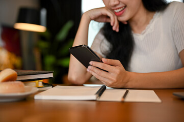 cropped, Beautiful young Asian female at the working table using her smartphone