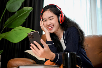 Fototapeta na wymiar Attractive female turns on the music from her playlist on a smartphone while wearing headphones.