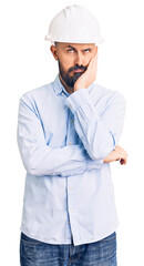 Young handsome man wearing architect hardhat thinking looking tired and bored with depression problems with crossed arms.