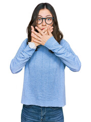 Young beautiful woman wearing casual clothes and glasses shocked covering mouth with hands for mistake. secret concept.