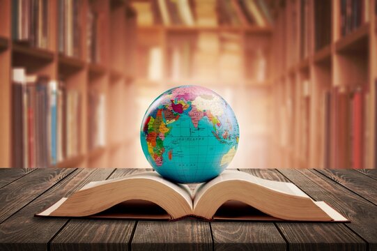 An open book against the background of bookshelves in a library. Science, education, travel. Education history and geography team.