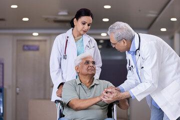 Doctors comforting disabled elderly patient
