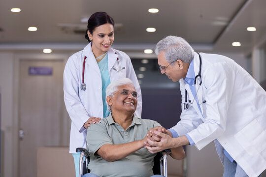 Doctors comforting disabled elderly patient

