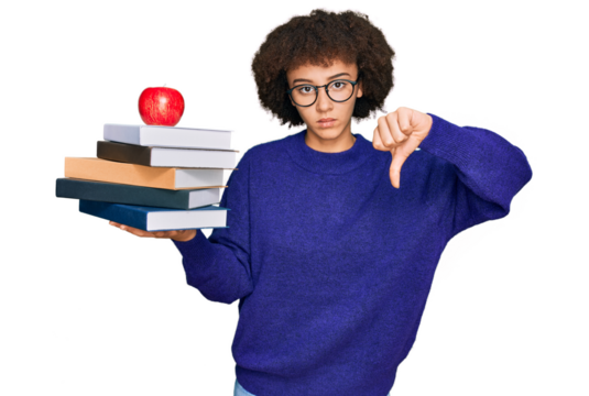 Young hispanic girl wearing glasses holding books and red apple with angry face, negative sign showing dislike with thumbs down, rejection concept